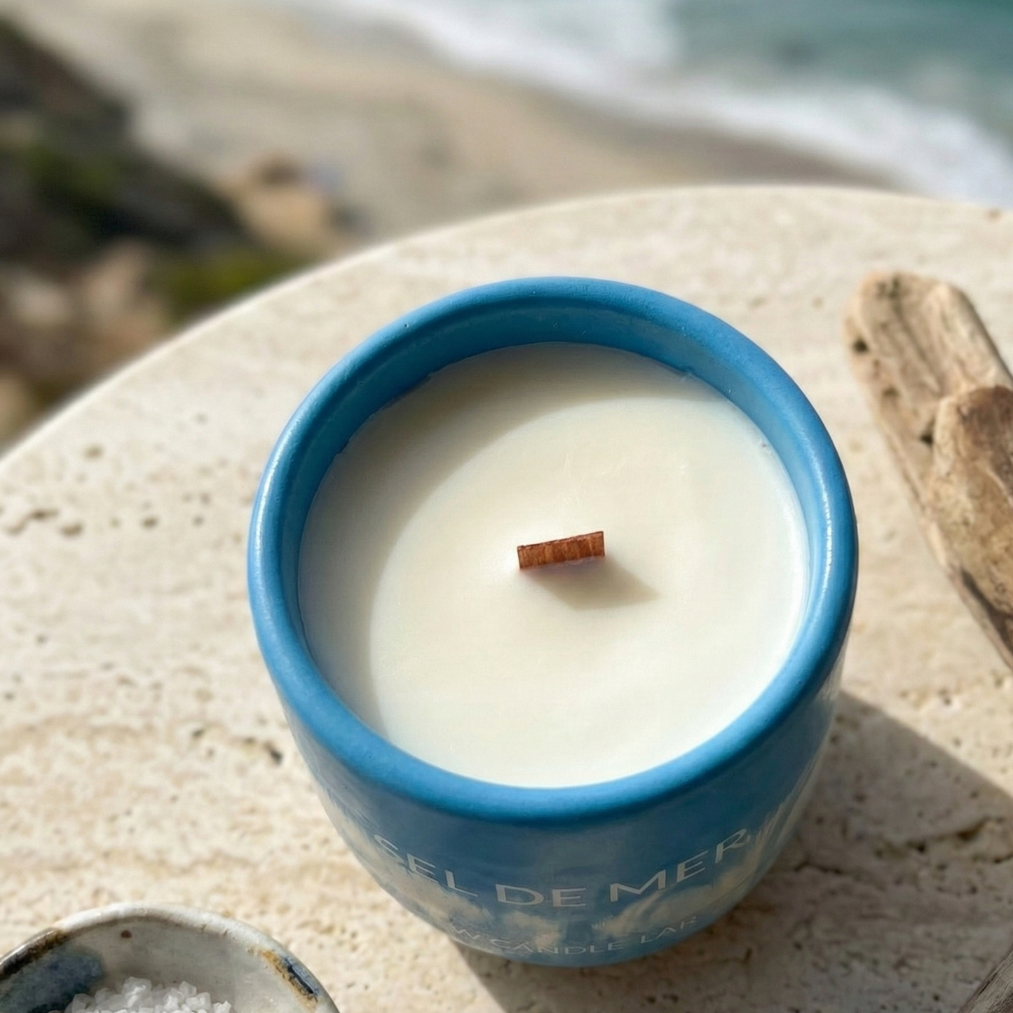 Sel de Mer sea salt candle styled with sea salt crystals and driftwood overlooking the coastline.