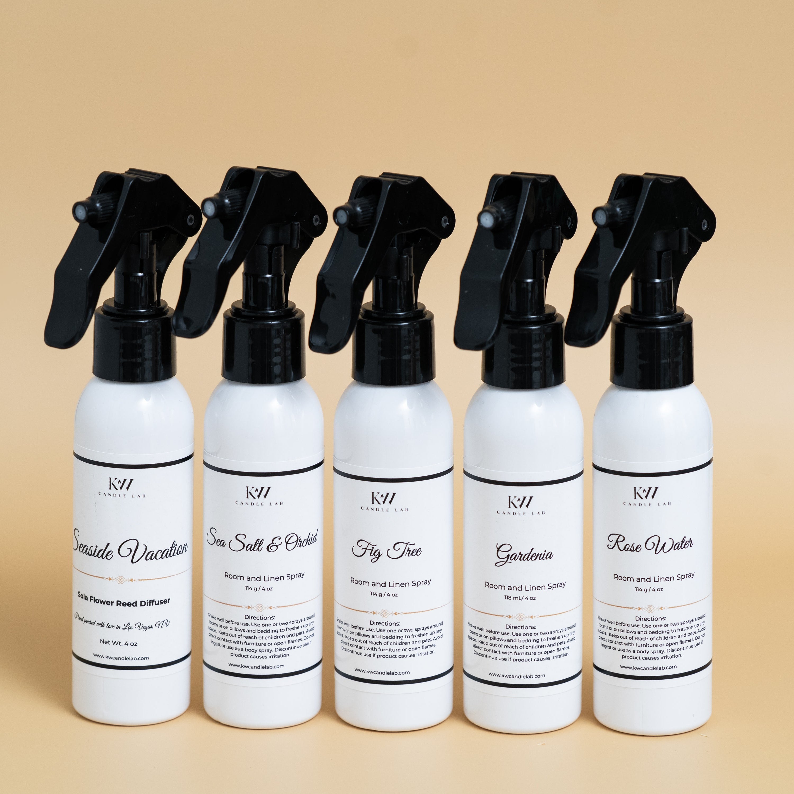 Set of five kw candle lab white room spray bottles with black nozzles on a beige background