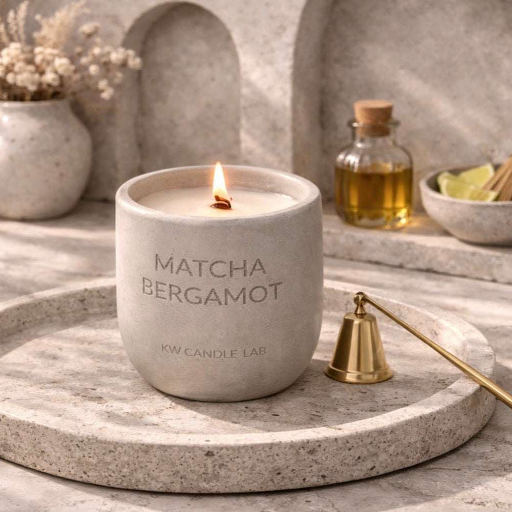 KW candle Lab Matcha Bergamot concrete candle on a stone tray with decorative items in the background