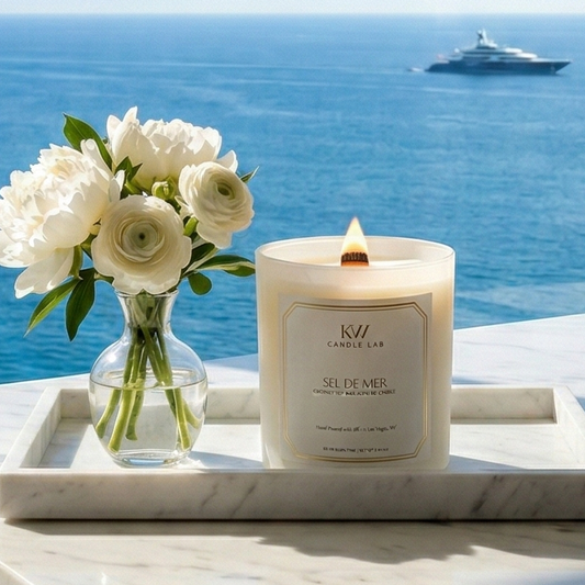 Sel de Mer sea salt candle with ocean view and fresh white florals styled on a marble tray.